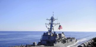 naval destroyer sailing at sea with flag flying