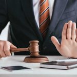 Judge with gavel raising hand in stop gesture