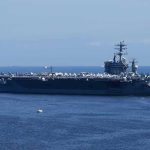 Aircraft carrier at sea with crew lining the deck