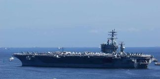 Aircraft carrier at sea with crew lining the deck