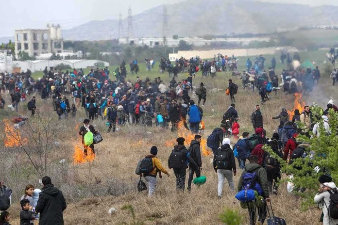 Large crowd of people walking through a field with small fires
