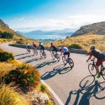 Cyclists ride downhill on a coastal mountain road