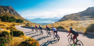 Cyclists ride downhill on a coastal mountain road