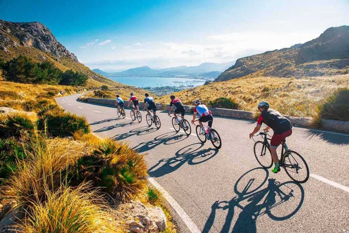 Cyclists ride downhill on a coastal mountain road