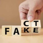 Hand flipping wooden blocks between fact and fake