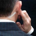 security agent with earpiece touching ear