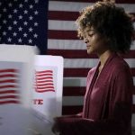 Voter at a polling booth with an American flag backdrop