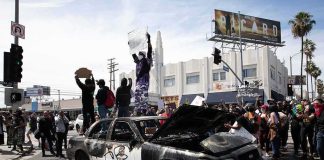 Damaged police car surrounded by protesters on a city street
