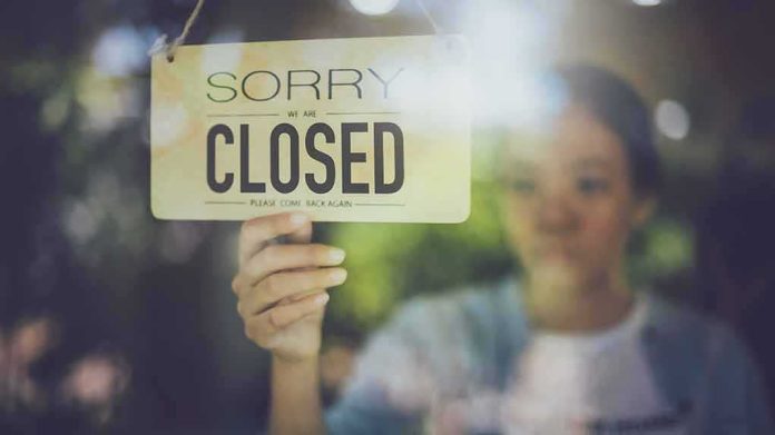 Person holding a closed sign on a shop window