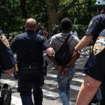 Police escort a handcuffed man across a city street