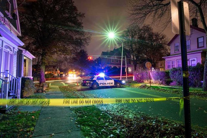 Police car blocks residential street at night behind caution tape