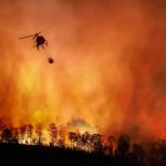 Helicopter fights massive wildfire over burning forest
