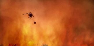 Helicopter fights massive wildfire over burning forest