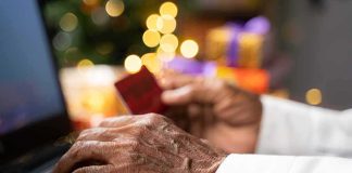 Hands using a laptop and holding a credit card