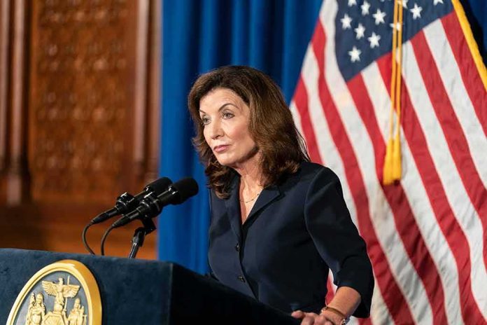 Woman at podium speaking with microphones and U.S. flag behind