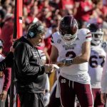 football coach and quarterback confer on sideline
