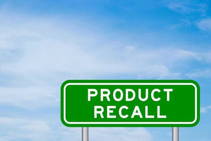 Green road sign reading product recall against blue sky