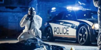 forensic investigator photographing crime scene near police car