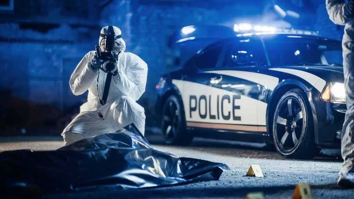 forensic investigator photographing crime scene near police car
