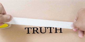 hands placing white tape over the word TRUTH on cardboard
