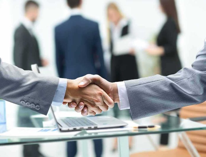 Businessmen handshake over a glass desk