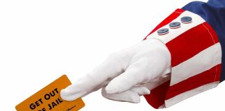 gloved hand in red and white striped sleeve holding a get out of jail card