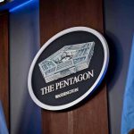 The Pentagon emblem between two flags.