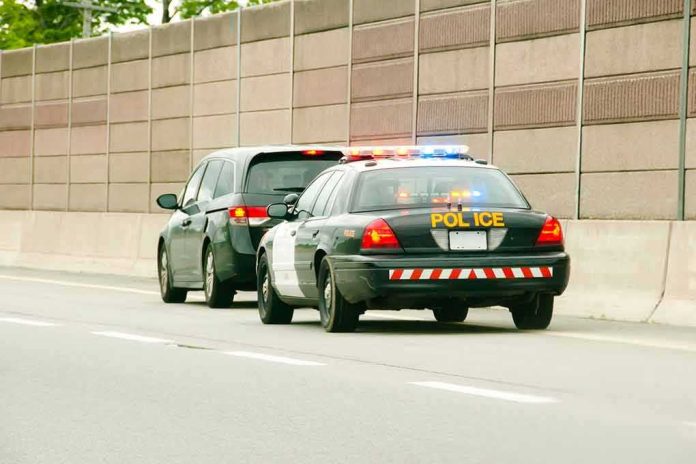 shutterstock_1006978648-1 Police car with flashing lights stops a minivan on highway