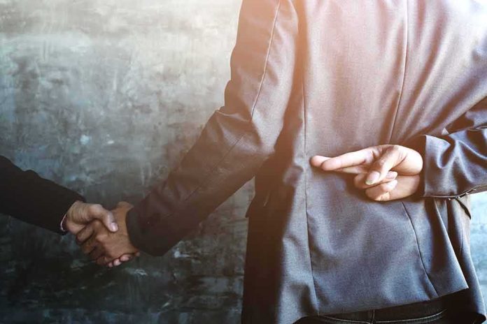 businessperson shakes hands while crossing fingers behind back
