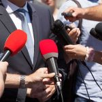 He Put America Below Al-Qaeda — Two 2028 Hopefuls Split Over HIM Person in suit surrounded by microphones during media interview