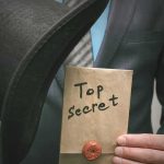 Person in suit holding a top hat and sealed envelope