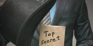 Person in suit holding a top hat and sealed envelope