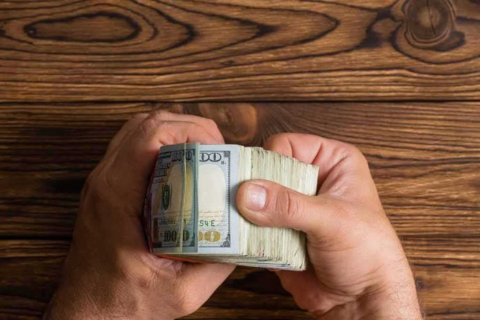 Hands holding a thick stack of U.S. hundred-dollar bills