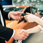 Handshake and car keys changing hands in a showroom