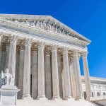 Supreme Court building with tall marble columns under a clear blue sky