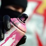 gloved hand holding a pink spray paint can