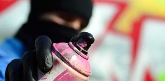 gloved hand holding a pink spray paint can
