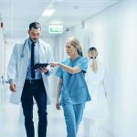 King Dead, New King Instantly Doctor and nurse walking in a hospital corridor reviewing a tablet