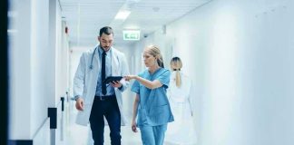 Doctor and nurse walking in a hospital corridor reviewing a tablet