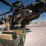 attack helicopter on tarmac with crew and ammunition crates