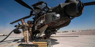 attack helicopter on tarmac with crew and ammunition crates