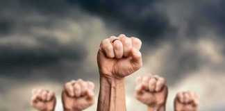Raised fists against a cloudy sky