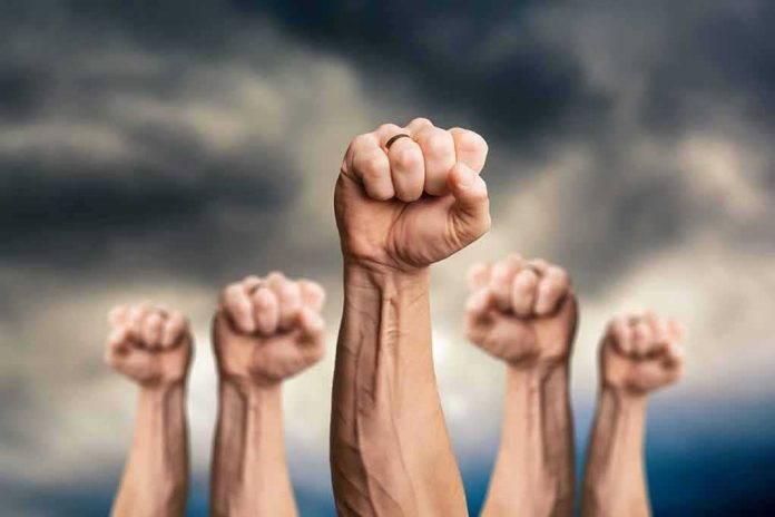 Raised fists against a cloudy sky