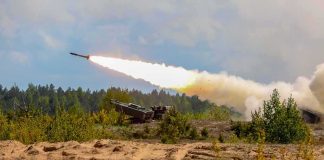rocket artillery launcher firing in a sandy field