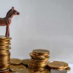 Plastic donkey figurine on a stack of coins