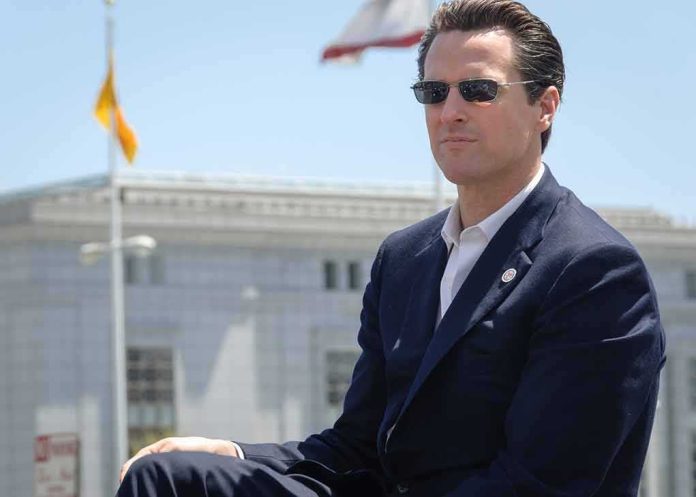 shutterstock_1593449839-1 Gavin Newsom wearing sunglasses in a navy suit outdoors