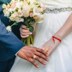 Couple's hands with wedding rings and bouquet