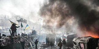 A chaotic protest scene with smoke, fire, and people holding flags
