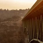 Steel truss bridge spanning a canyon at sunset
