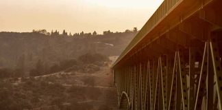 Steel truss bridge spanning a canyon at sunset